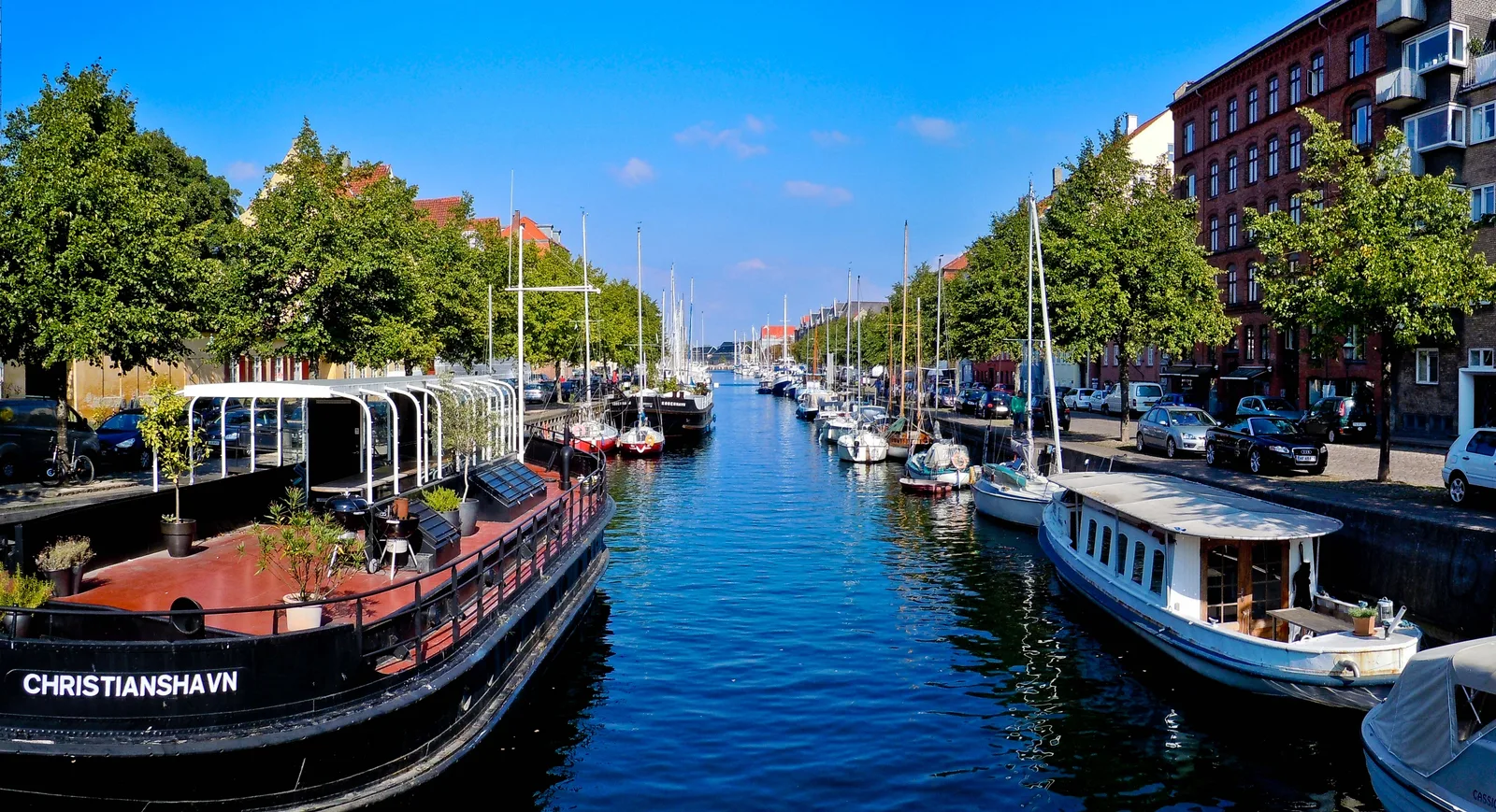 Electric boat on Copenhagen canal during spring, with historic buildings and clear water visible