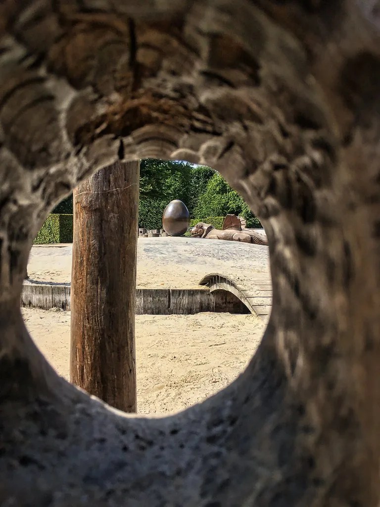 Wooden adventure playground with climbing structures in lush green garden setting in Copenhagen